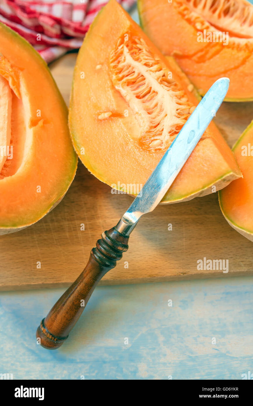 Melone fette di melone e il coltello sulla tavola in legno rustico, il fuoco selettivo Foto Stock