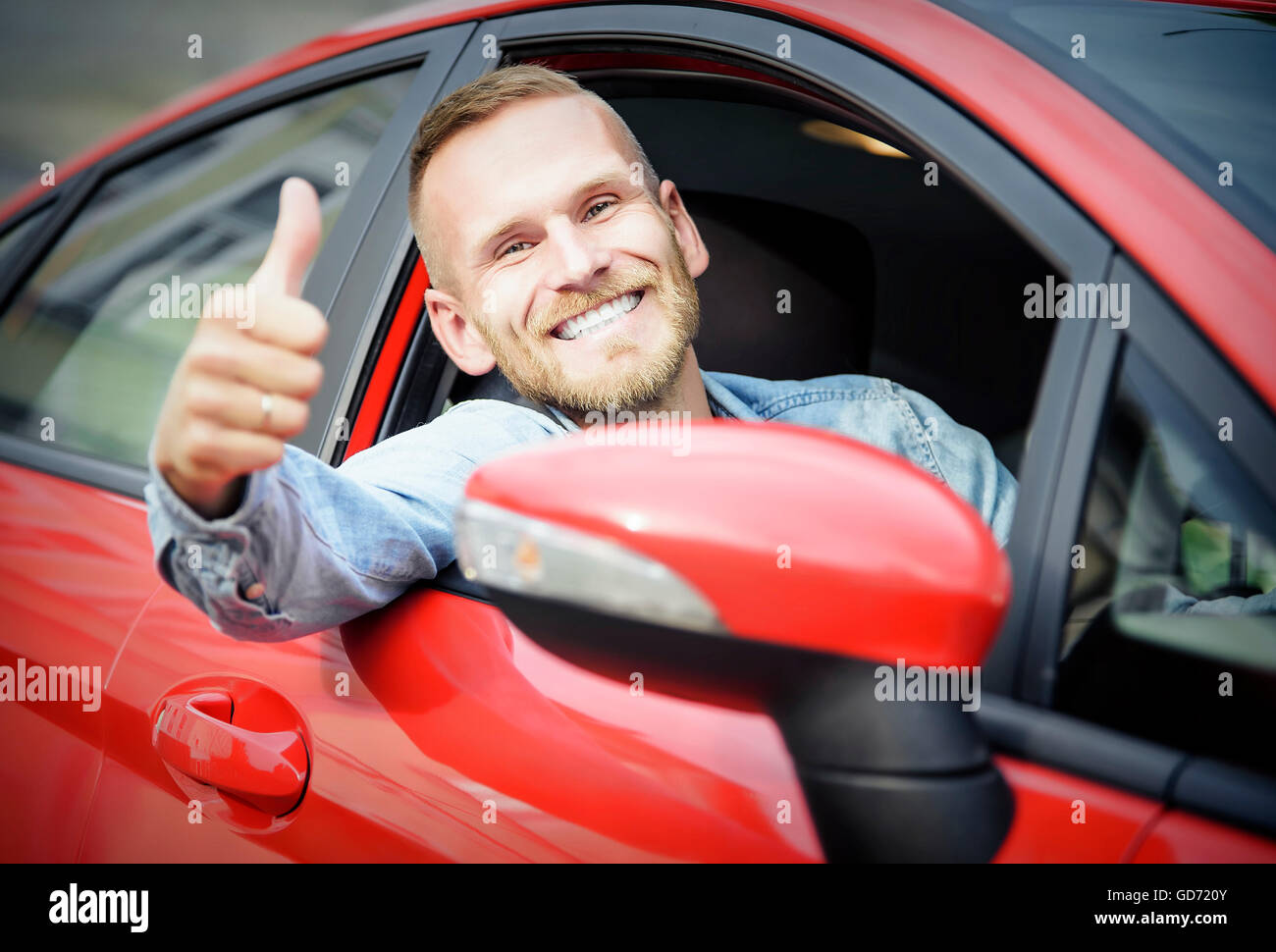 Uomo al volante della sua nuova vettura, mostrando il pollice verso l'alto. Foto Stock