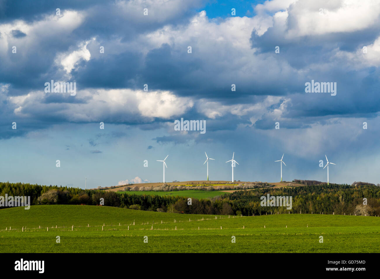 Il paesaggio agricolo con impianti di energia eolica, alberi verdi campi e nuvoloso cielo blu, Hausdorf, Bassa Sassonia, Germania Foto Stock