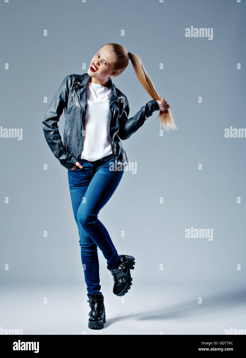 Modello di moda tirando i suoi capelli in coda e guardando la fotocamera Foto Stock