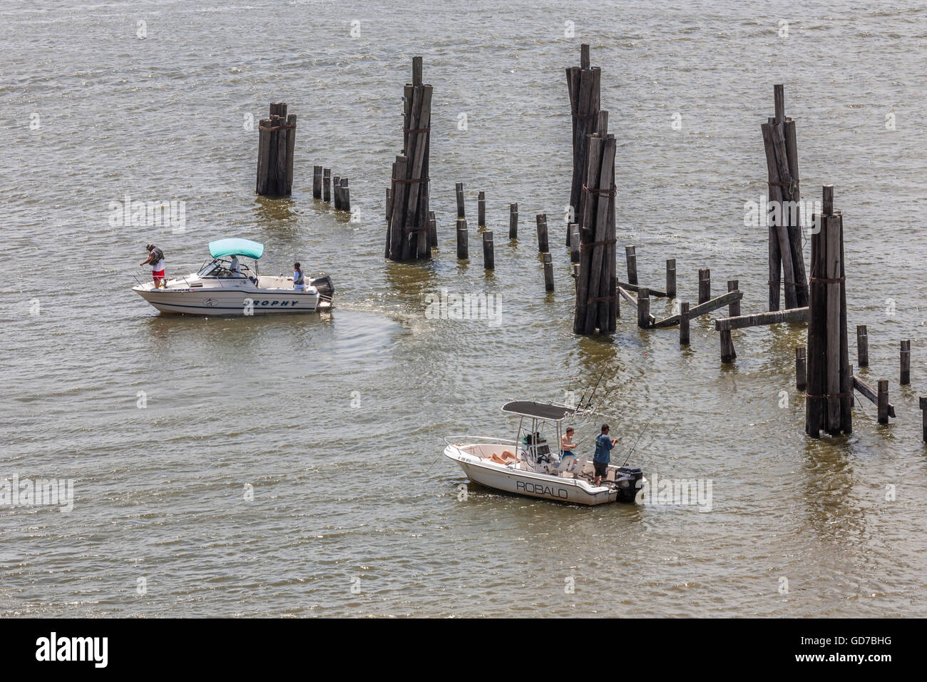 Gli uomini la pesca dalle barche vicino a resti di legno molo pesca distrutto da un uragano in Biloxi Mississippi Foto Stock