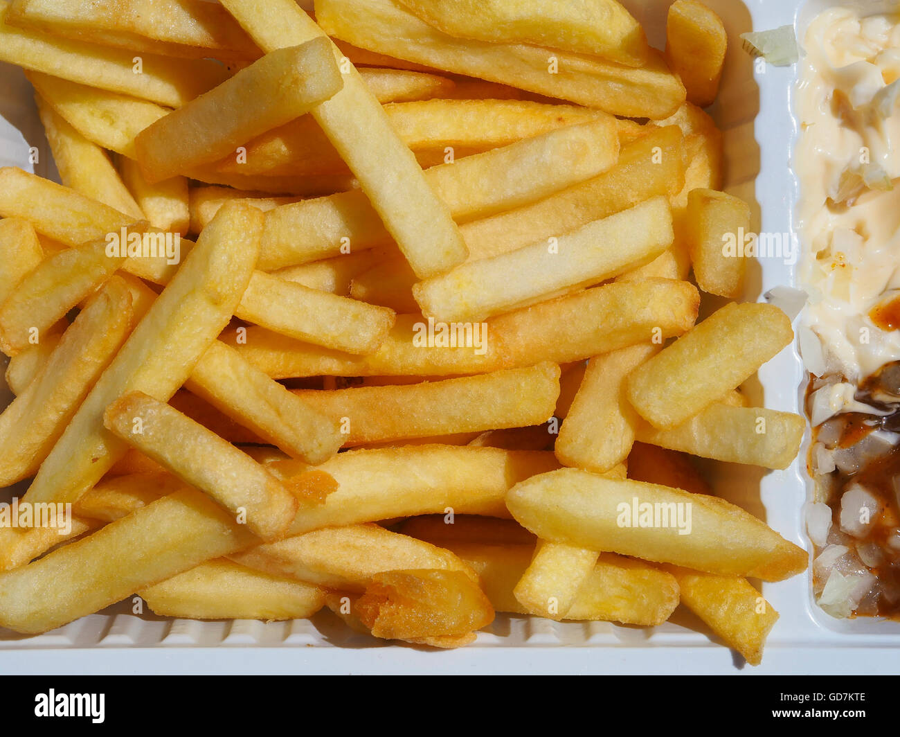 Close-up di golden francese-fried potato chips in un bianco piatto di plastica con maionese Foto Stock