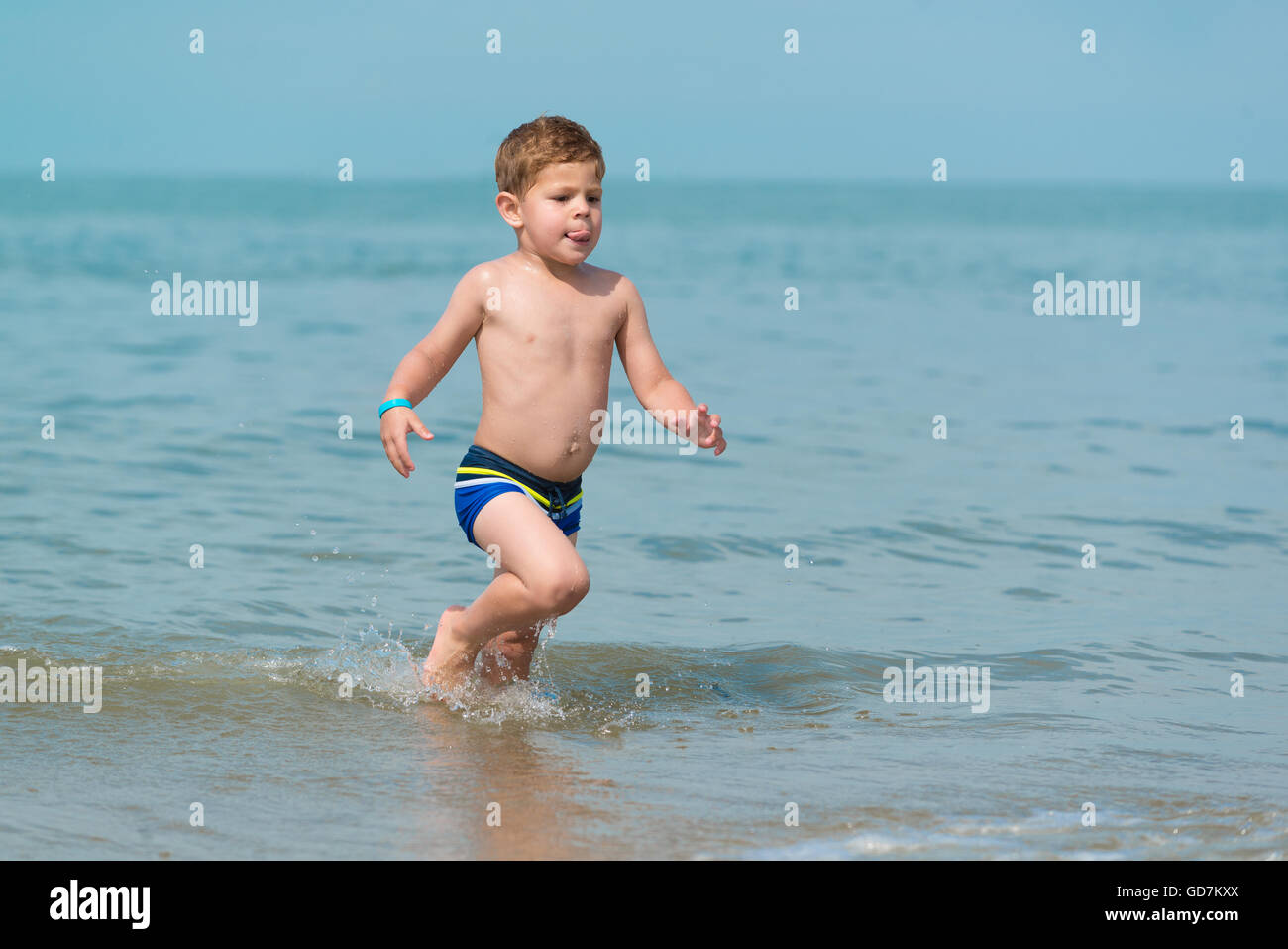 Little Boy bambino che corre attraverso il mare presso la spiaggia di onde  in pantaloncini corti la gioia della vita in vacanza Foto stock - Alamy