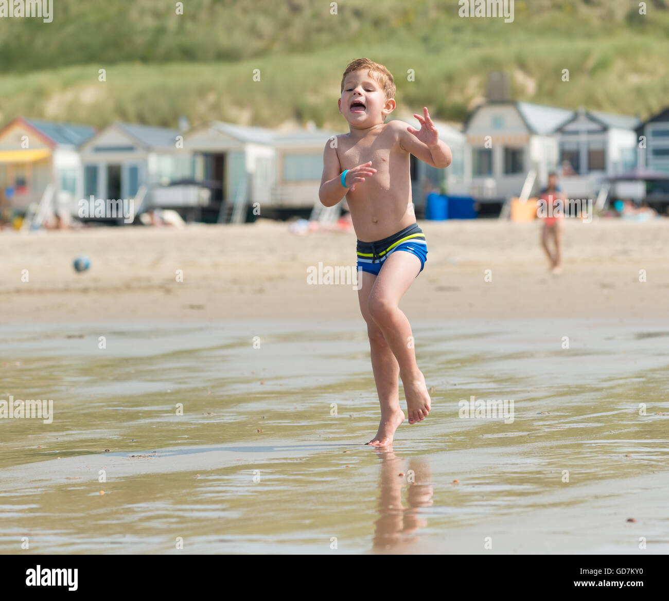Little Boy bambino che corre attraverso il mare presso la spiaggia di onde  in pantaloncini corti la gioia della vita in vacanza Foto stock - Alamy