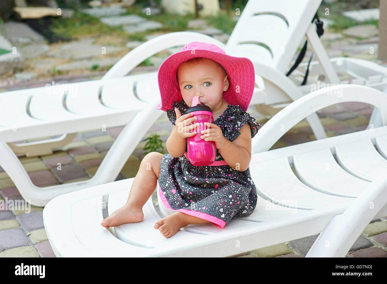 Little Girl in Red Hat si siede su una sedia a sdraio. Foto Stock