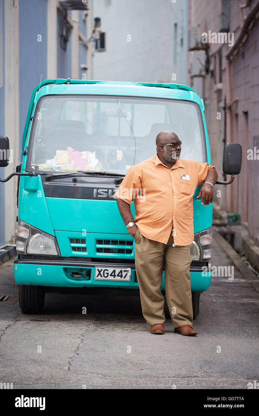 Barbados parrocchia di Saint Michael uomo locale maschio infantile di appoggio del suo verde Isuzu Truck in attesa Foto Stock