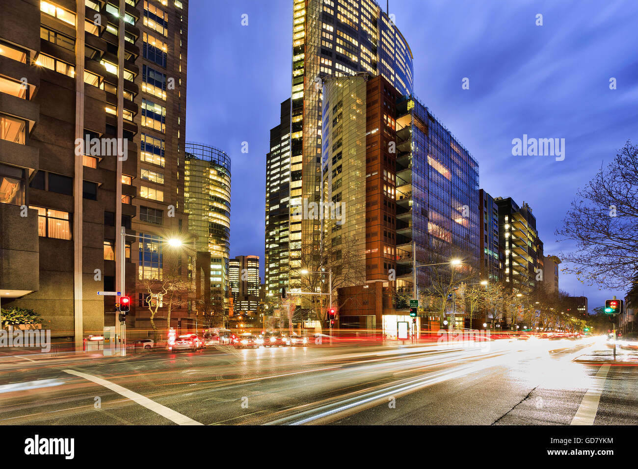 Occupato per le strade delle città del traffico in Sydney all'incrocio di Elizabeth Street illuminato con edifici per uffici a Rush Hour tramonto Foto Stock