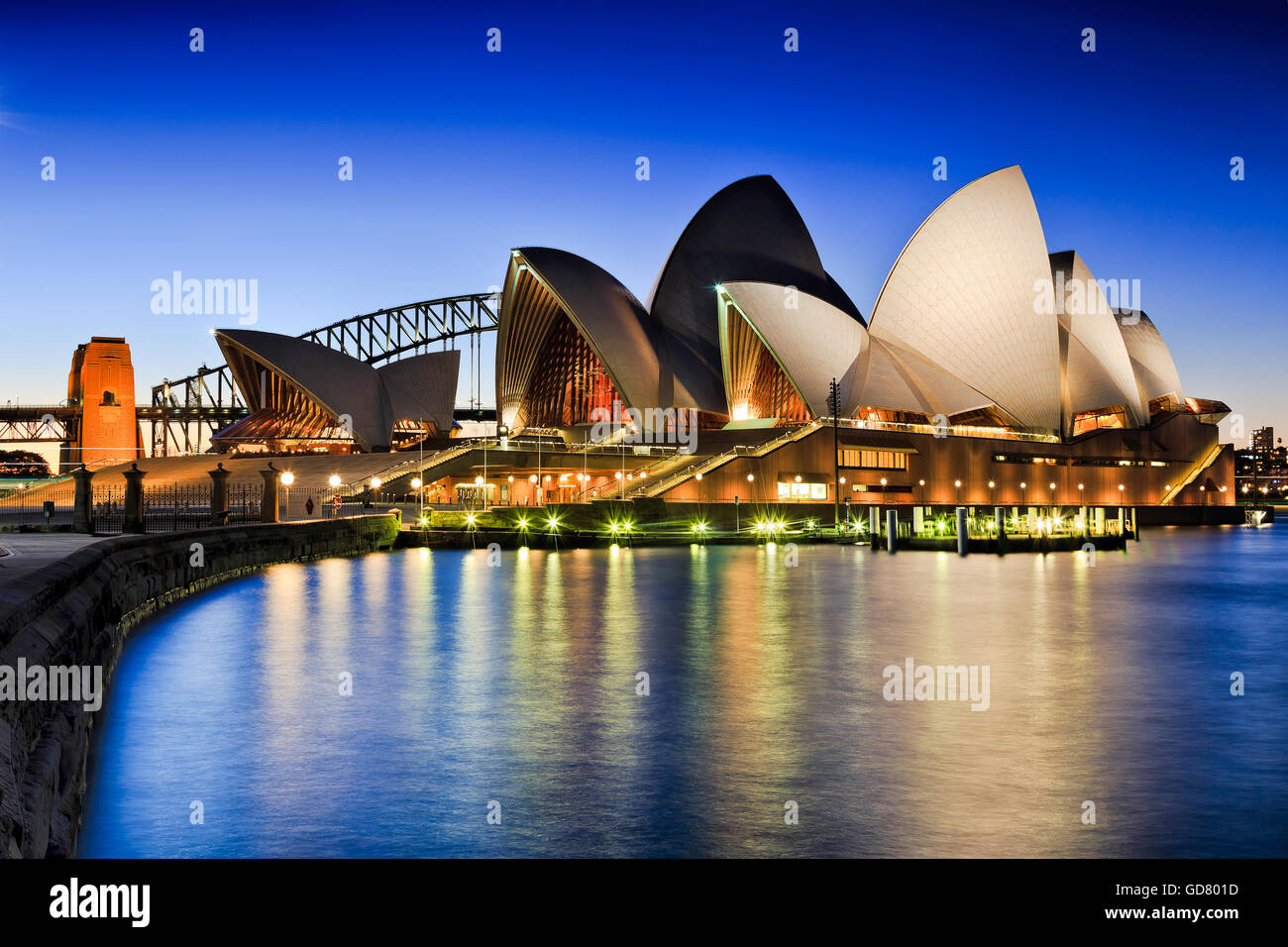 SYDNEY, AUSTRALIA, 1 luglio 2016 - Sydney Opera House e Harbour Bridge al tramonto che riflette le luci nella baia sfocata Foto Stock