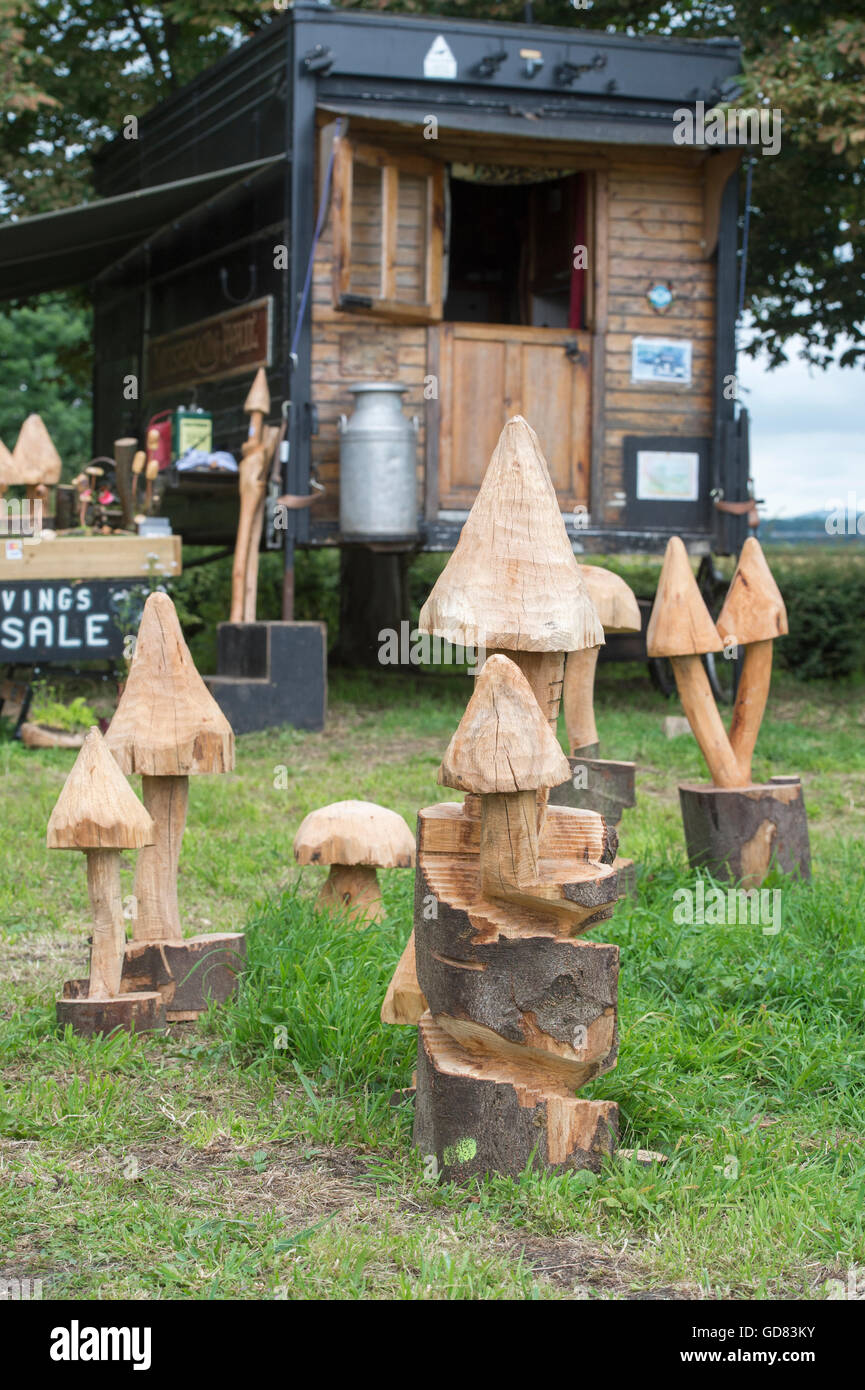 Fungo sculture in legno per la vendita nella parte anteriore di una roulotte in legno sul ciglio della strada. Cotswolds, Inghilterra Foto Stock