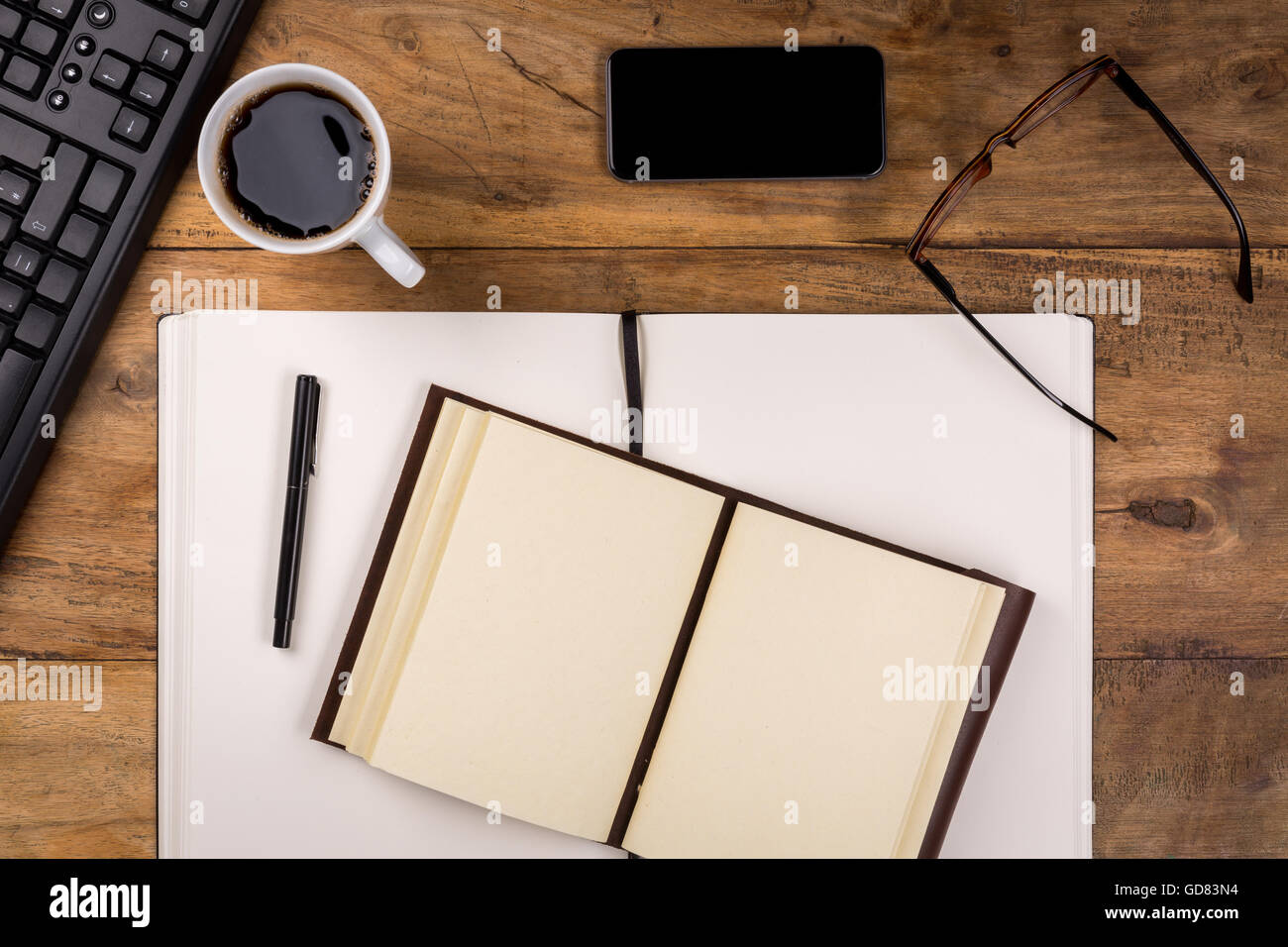 Ufficio in legno scrivania con tazza di caffè - tè, telefono cellulare, bicchieri, notebook, la penna e la tastiera del computer. Foto Stock