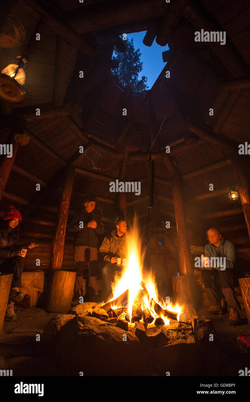 Gli escursionisti riscaldarsi intorno al fuoco a Brandheia Wilderness Camp Trøndelag Norvegia Europa Foto Stock