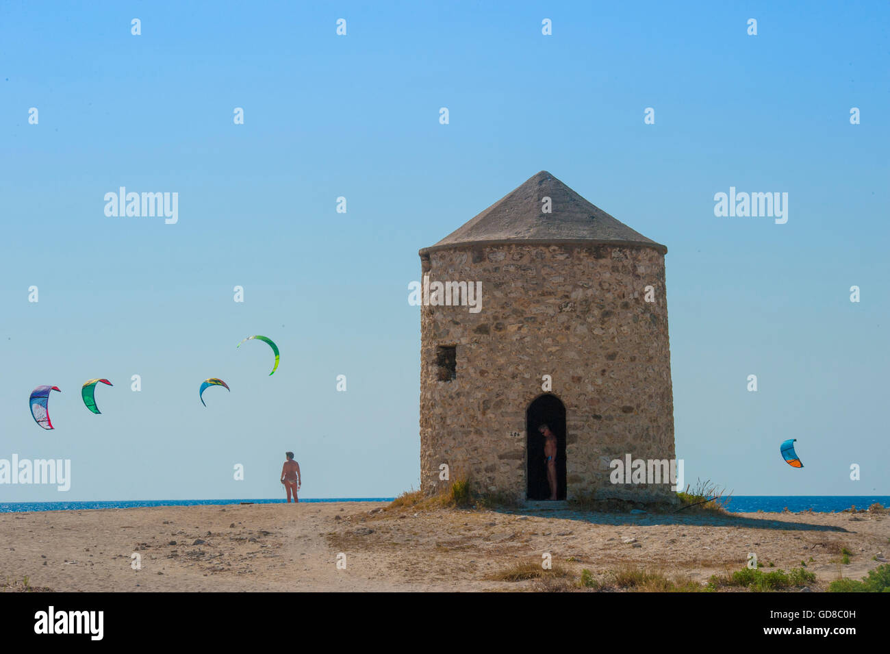 Vecchi Mulini a vento su una spiaggia popolata da surfisti e kitesurfisti in Lefkada, Lefkas Foto Stock