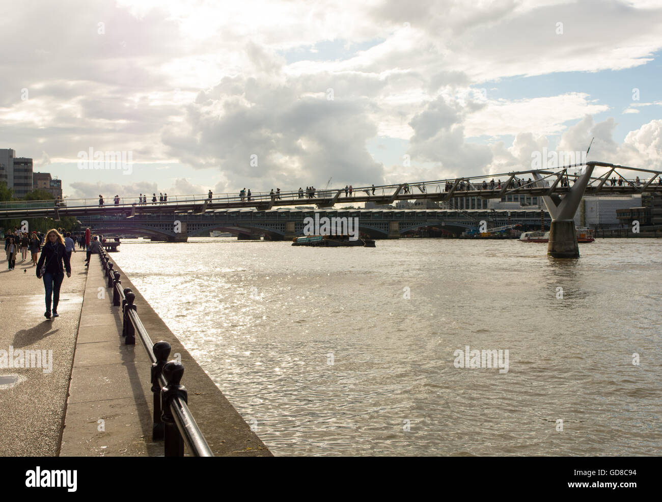 La luce diretta del sole sagome pedoni sul Millennium Bridge sul fiume Tamigi a Londra. Foto Stock