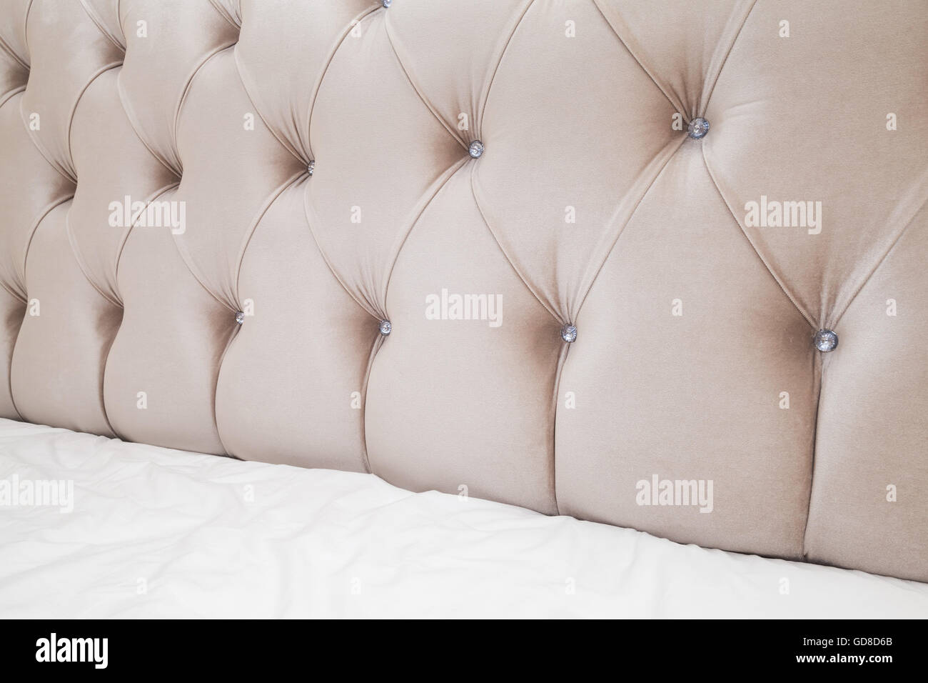 Lussuosa camera da letto vuoto frammento interno, rosa soffice testiera del letto e biancheria da letto bianca fogli su ampio letto matrimoniale Foto Stock