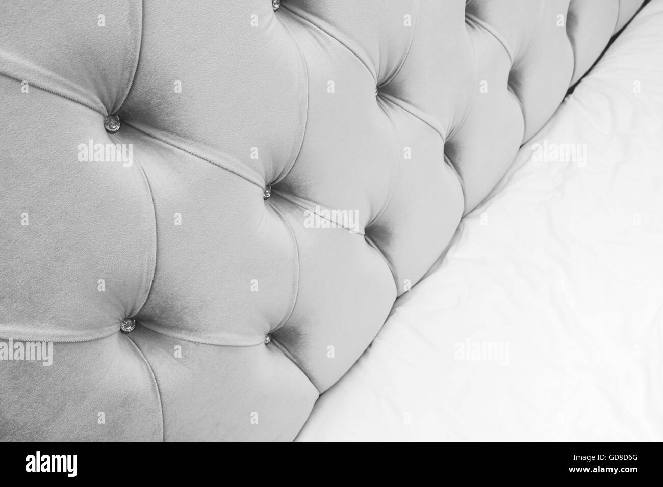 Lussuosa camera da letto vuoto frammento interno, grigio soffice testiera del letto e biancheria da letto bianca fogli su ampio letto matrimoniale Foto Stock