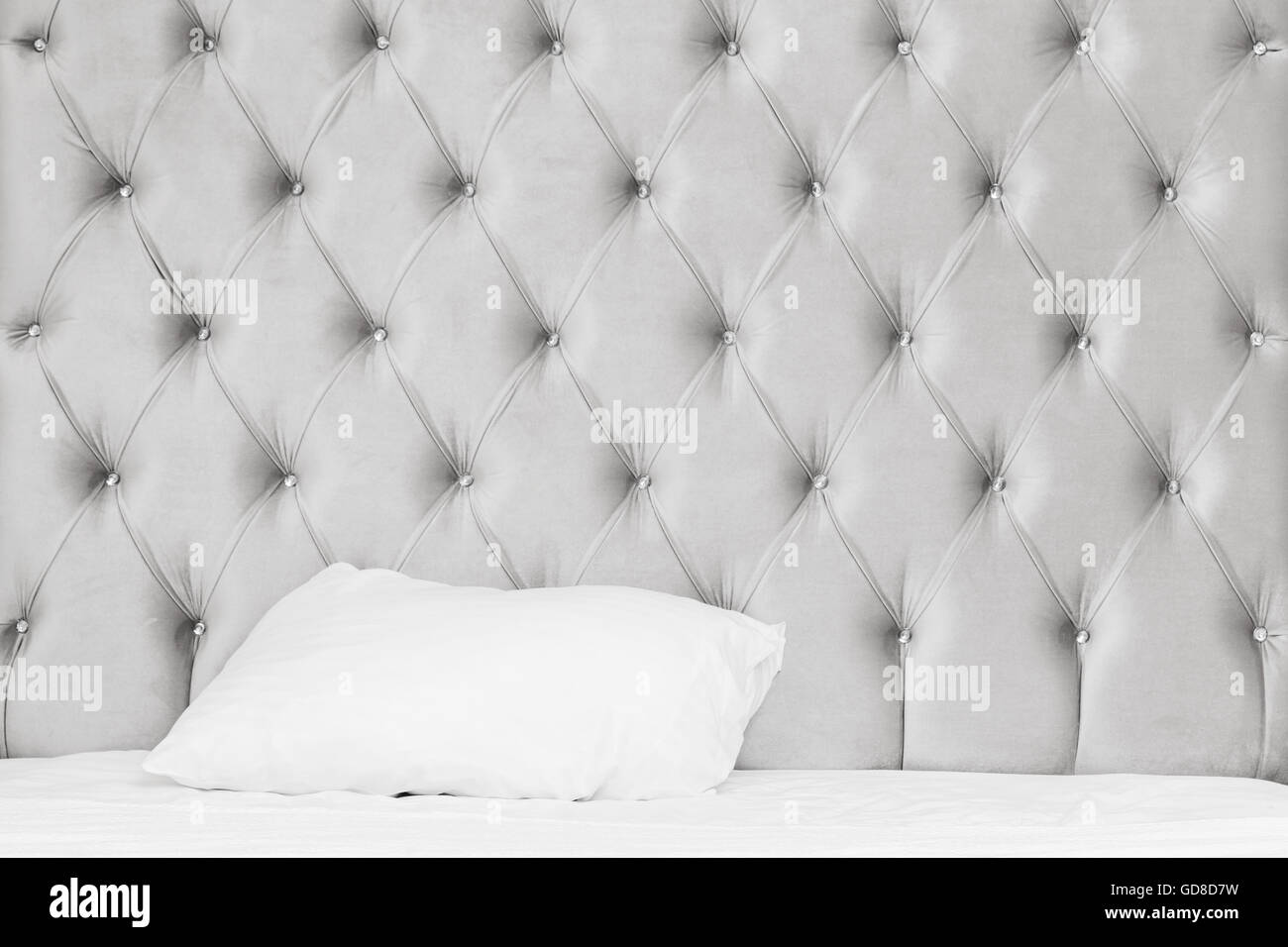 Lussuosa camera da letto vuoto frammento interno, morbido letto a parete, lenzuola bianche foglio e cuscino Foto Stock