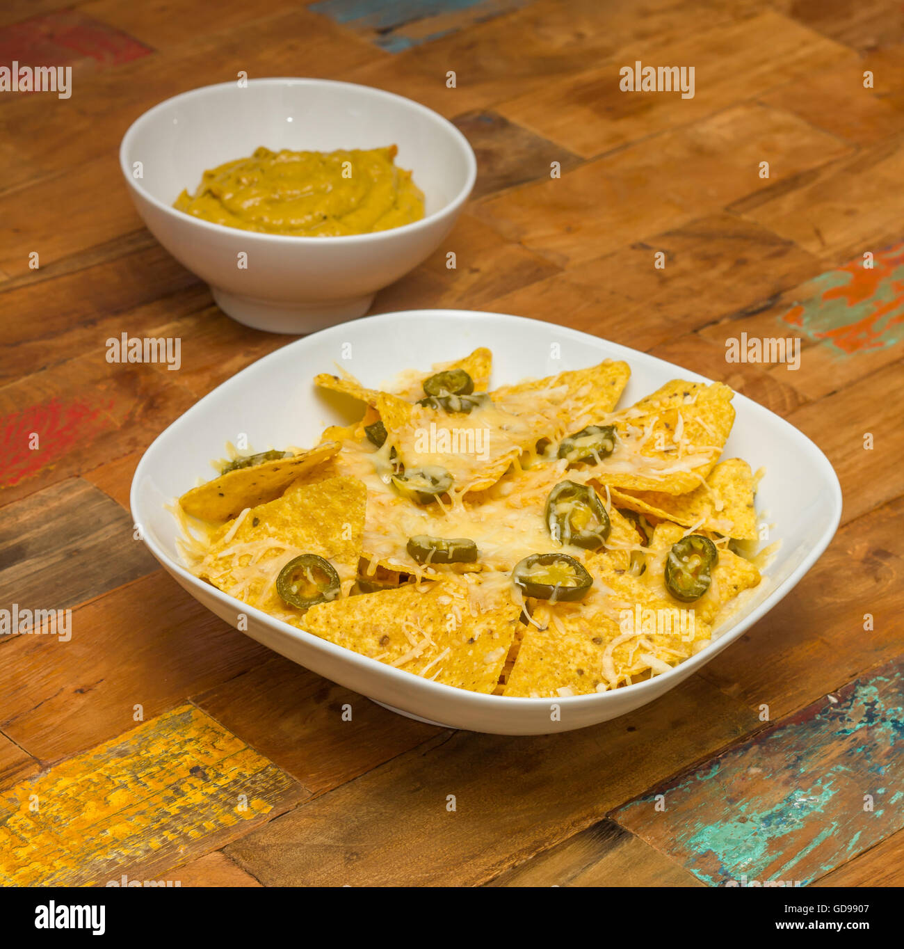 Nachos chips con formaggio e jalapenos in una ciotola bianco e Guacamole fresco Foto Stock