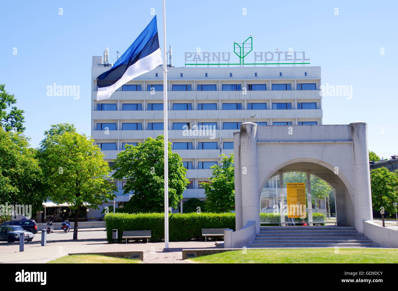 Bandiera estone sulla piazza principale di Pärnu con il monumento di indipendenza e hotel Pärnu in background Foto Stock