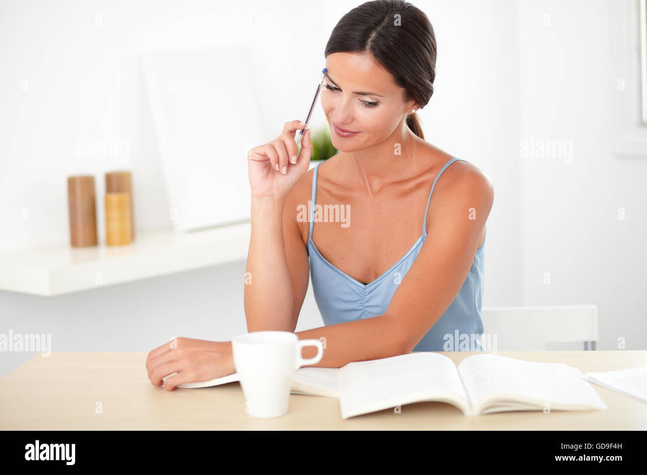 Bella persona di sesso femminile in blu camicetta lavora con libri nella sua casa Foto Stock
