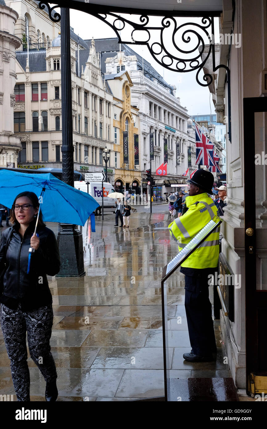 Un poliziotto britannico sulla battuta in un giorno di pioggia nella città di Londra Foto Stock