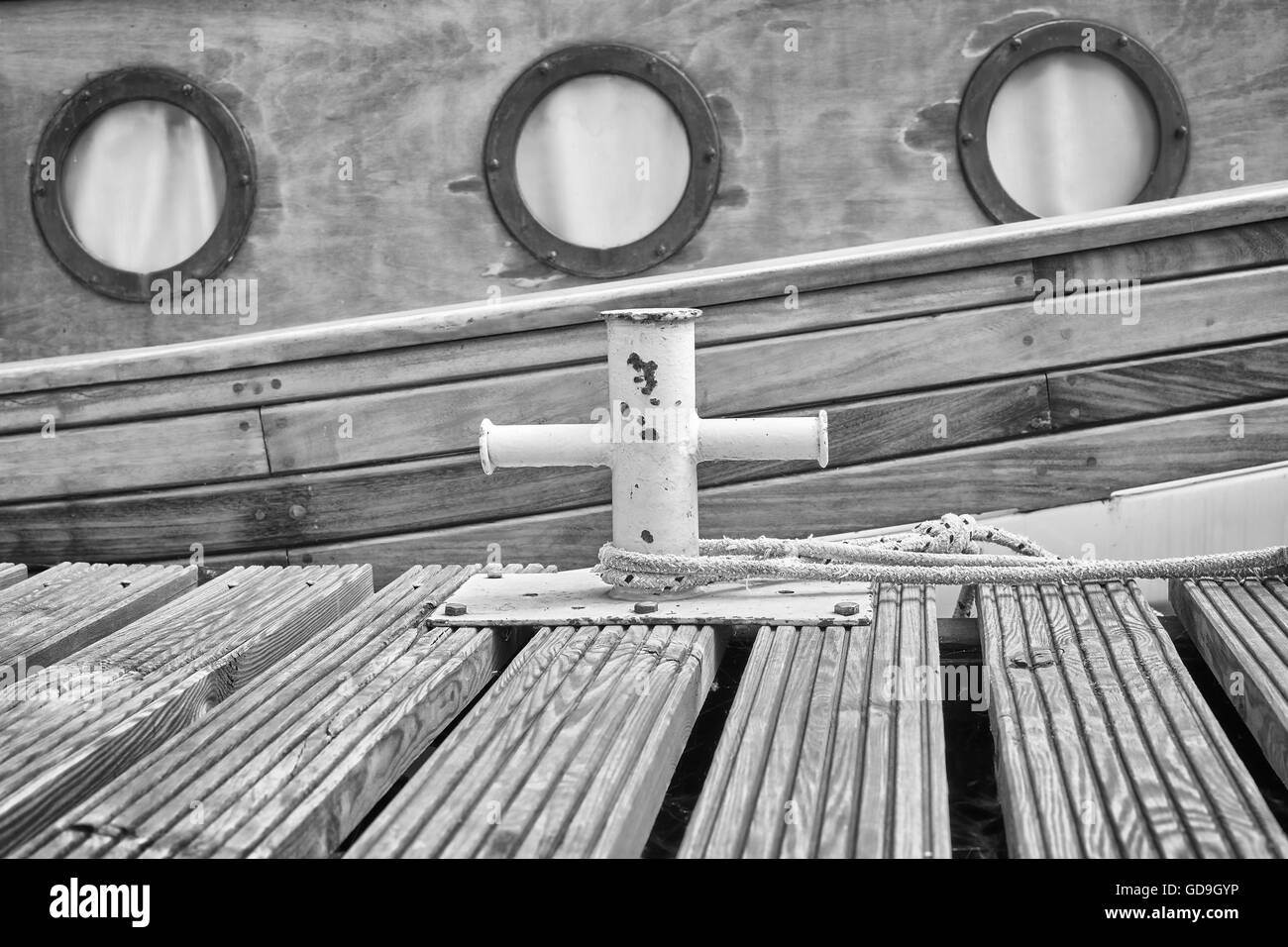 Foto in bianco e nero di una barca di legno ormeggiata a bollard in marina, sfondo nautico. Foto Stock