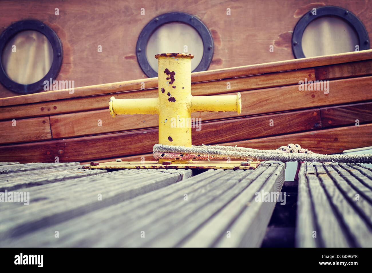 Vintage stilizzata in barca di legno ormeggiata a bollard in marina, sfondo nautico. Foto Stock