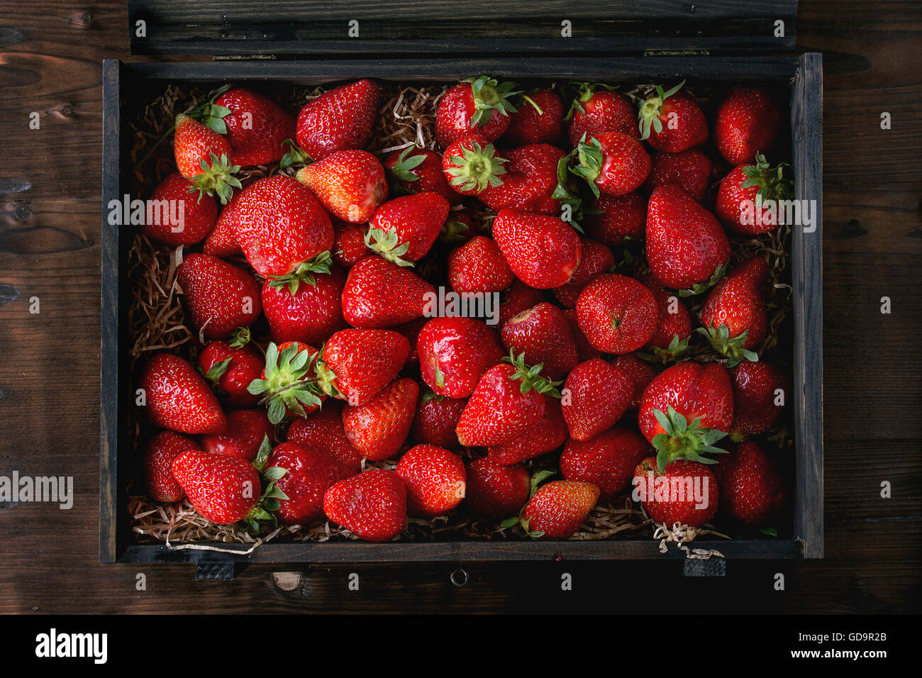 Fresche e mature di fragole succo di frutta in scatola di legno su legno scuro dello sfondo. Vista superiore Foto Stock