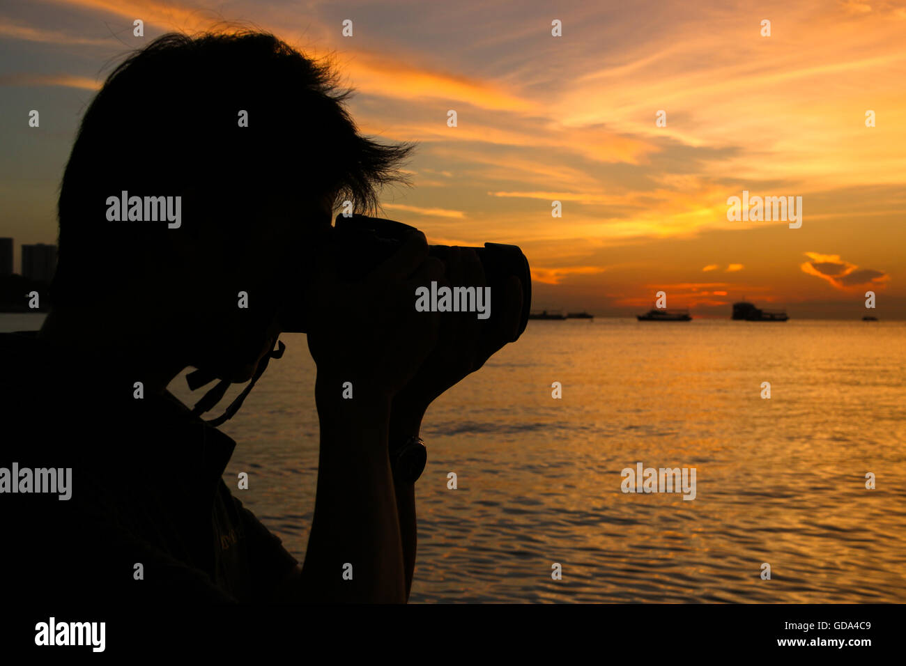 Silhouette di fotografo al tramonto sulla spiaggia di Pattaya, Thailandia Foto Stock