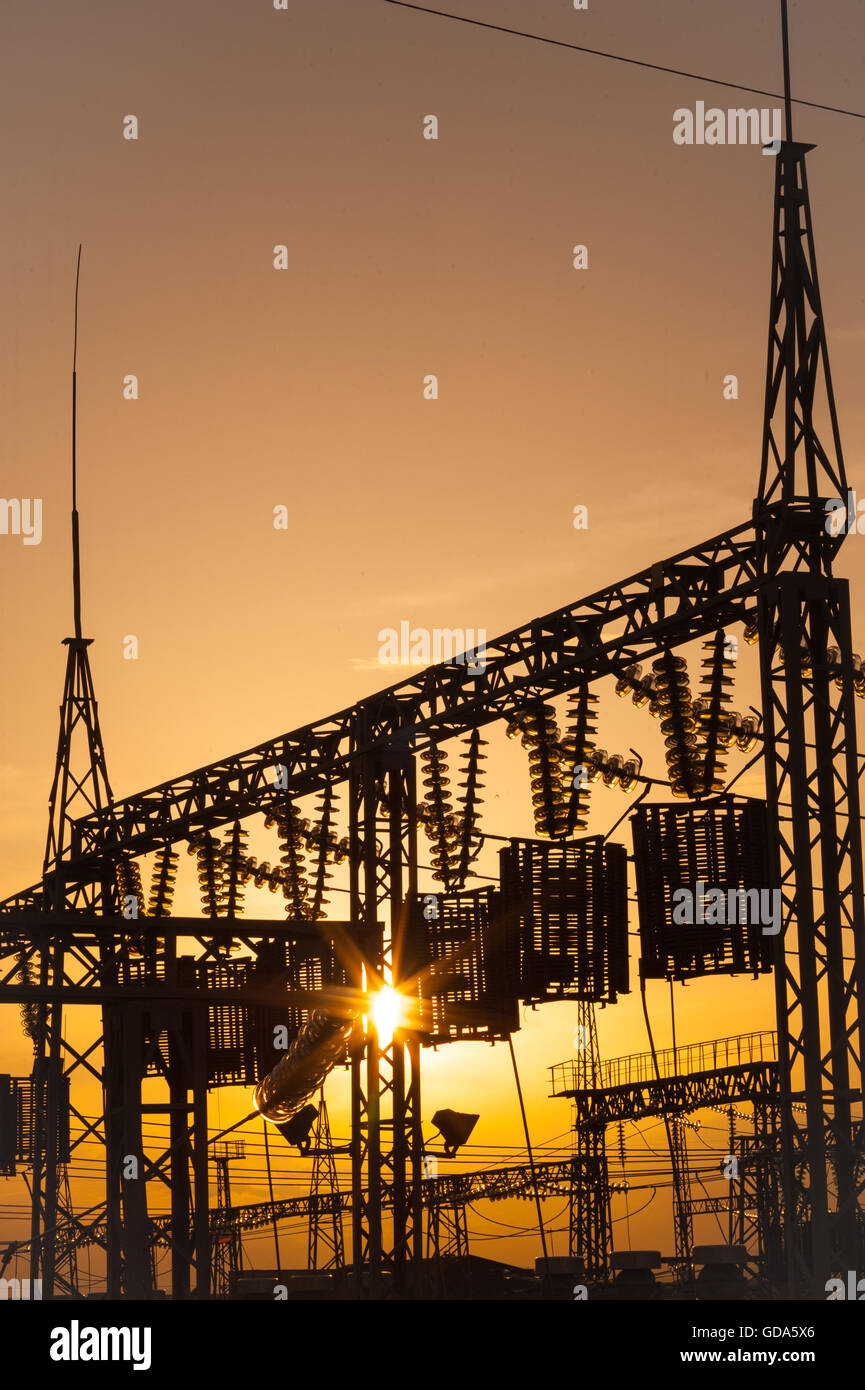 Le linee elettriche, i poli e gli isolatori di vetro in una stazione di alimentazione al tramonto Foto Stock