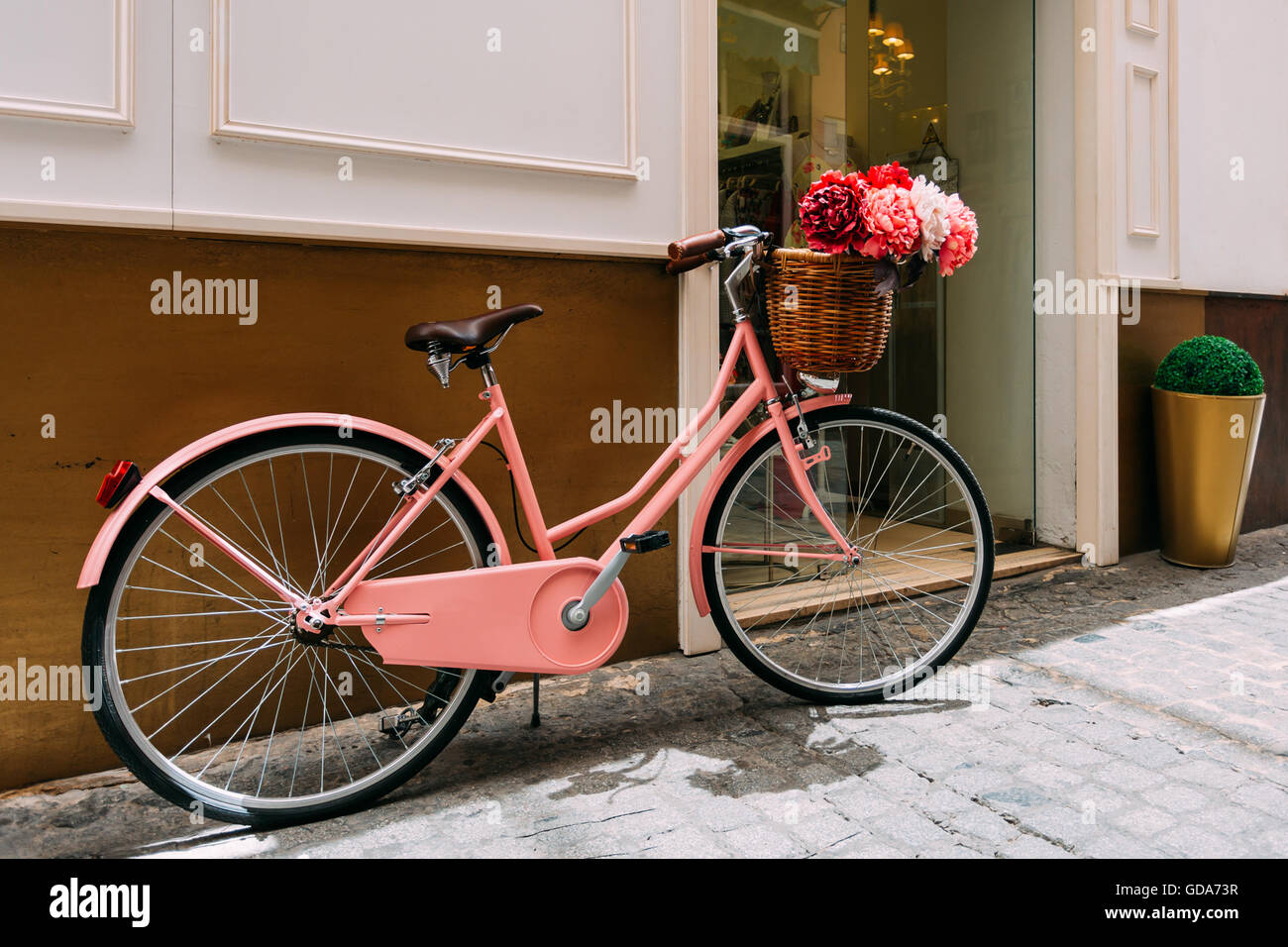 Vintage bicicletta rosa decorativa con un cesto di fiori sul parcheggio  flowersIn città europea Foto stock - Alamy