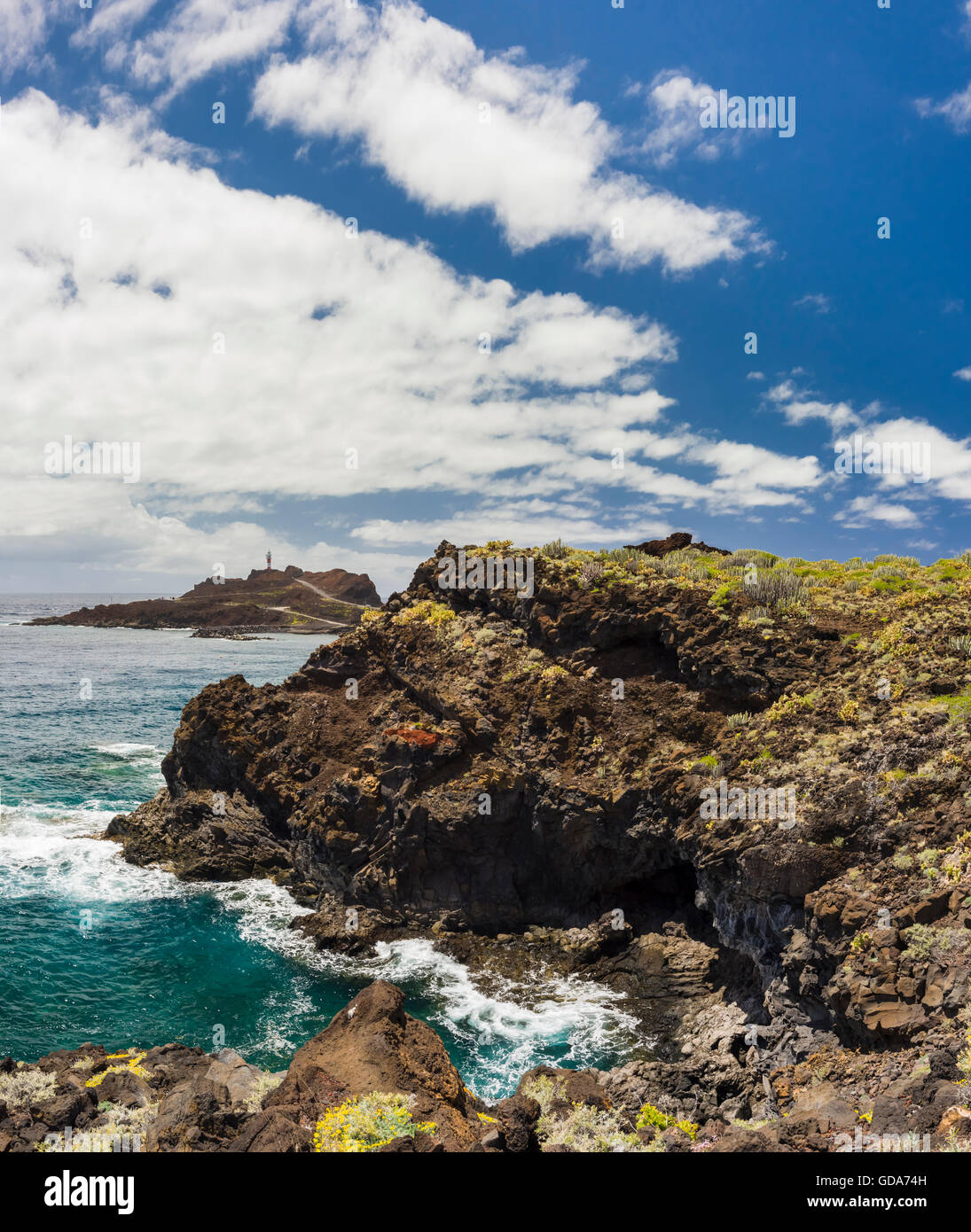 Il litorale roccioso a Punta de Teno nel nord-ovest di Tenerife con la Punta de Teno faro in background Foto Stock