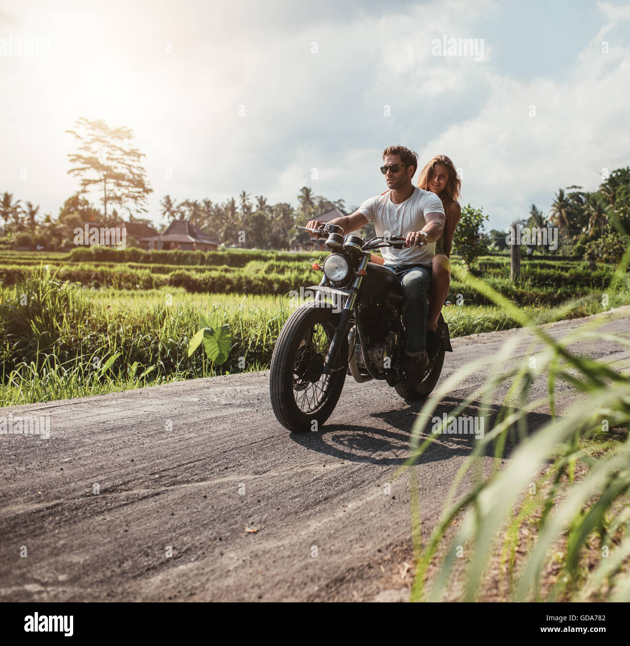 Colpo all'aperto del giovane in moto la guida attraverso la strada di campagna. L uomo e la donna in sella motocicletta su una strada di campagna. Foto Stock