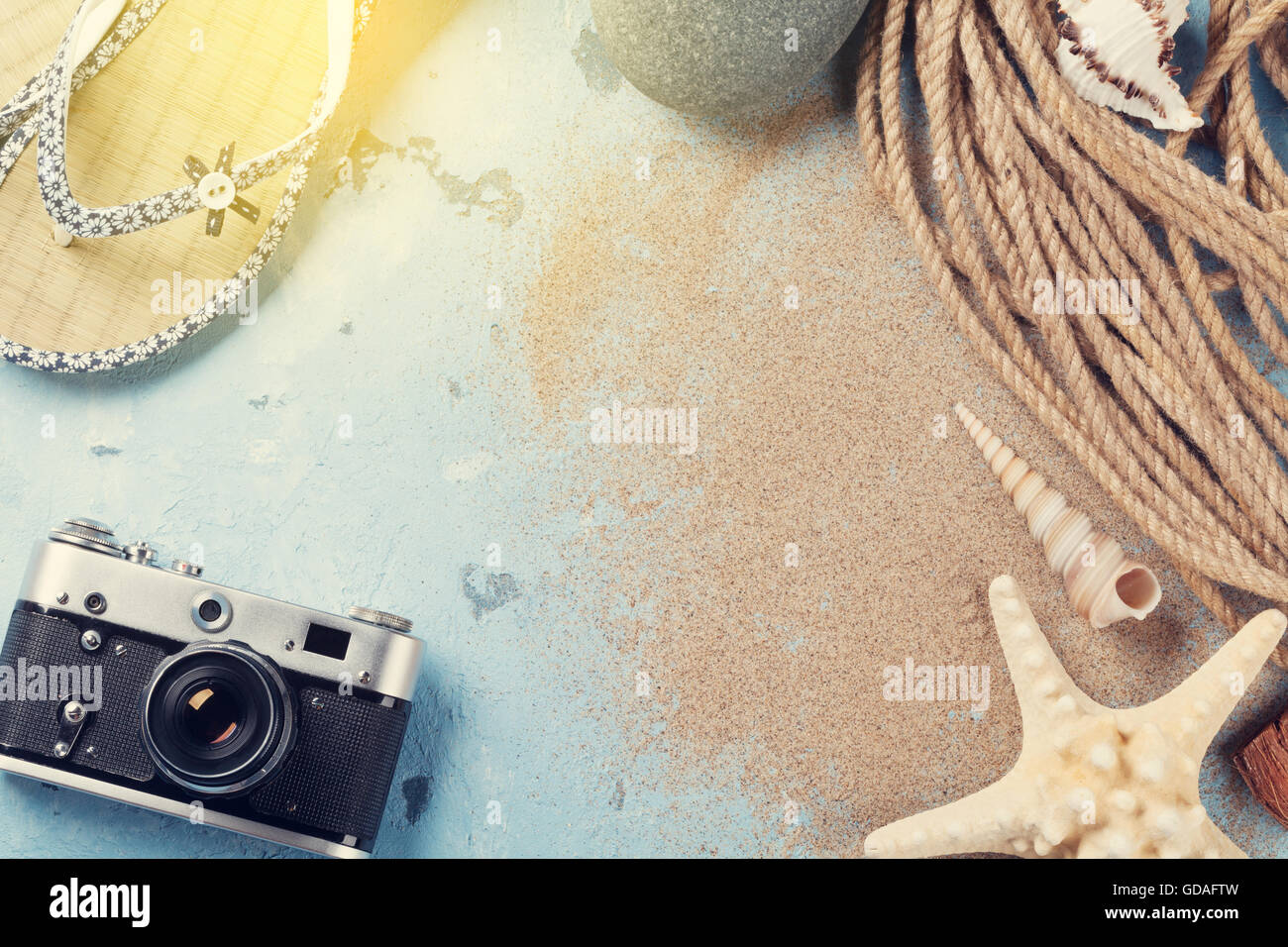 Vacanza al mare sullo sfondo. Fotocamera, stelle marine e flip-flop su uno sfondo di pietra con sabbia. Vista da sopra con copia spazio. Sunny tonica Foto Stock