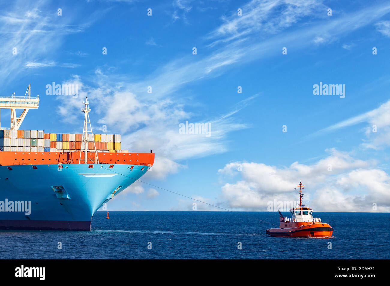 Rimorchiatore a traino il traino di un contenitore grande nave sul mare. Foto Stock