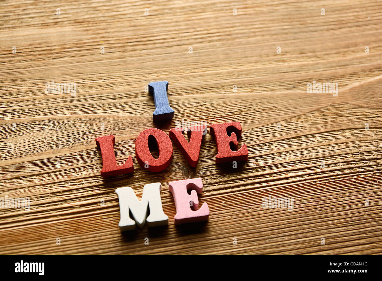 I LOVE ME- parola fatta dal variopinto lettere sullo sfondo di legno di colore caldo Foto Stock