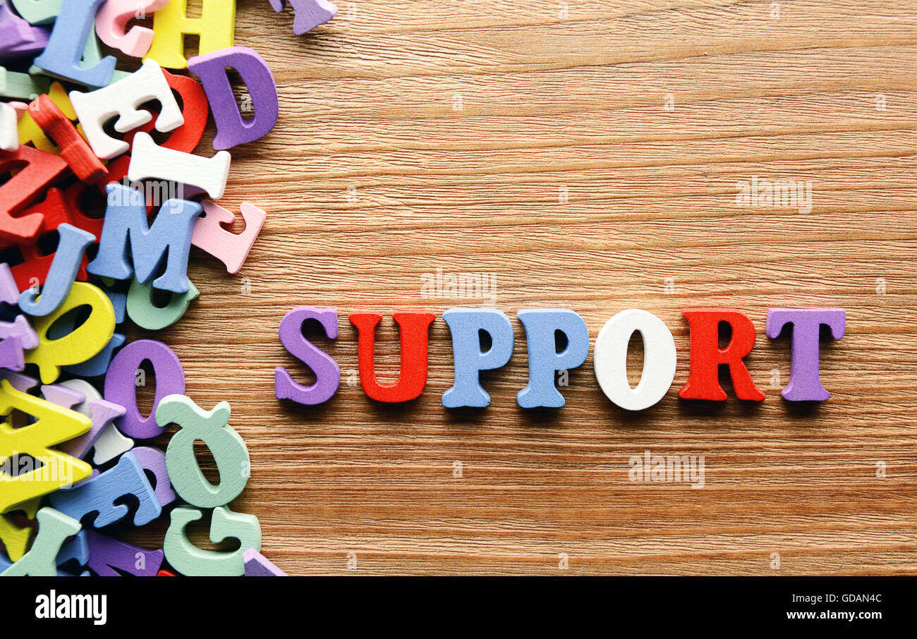 Supporto - parola fatta da multicolore giocattolo bambino lettere sullo sfondo di legno Foto Stock