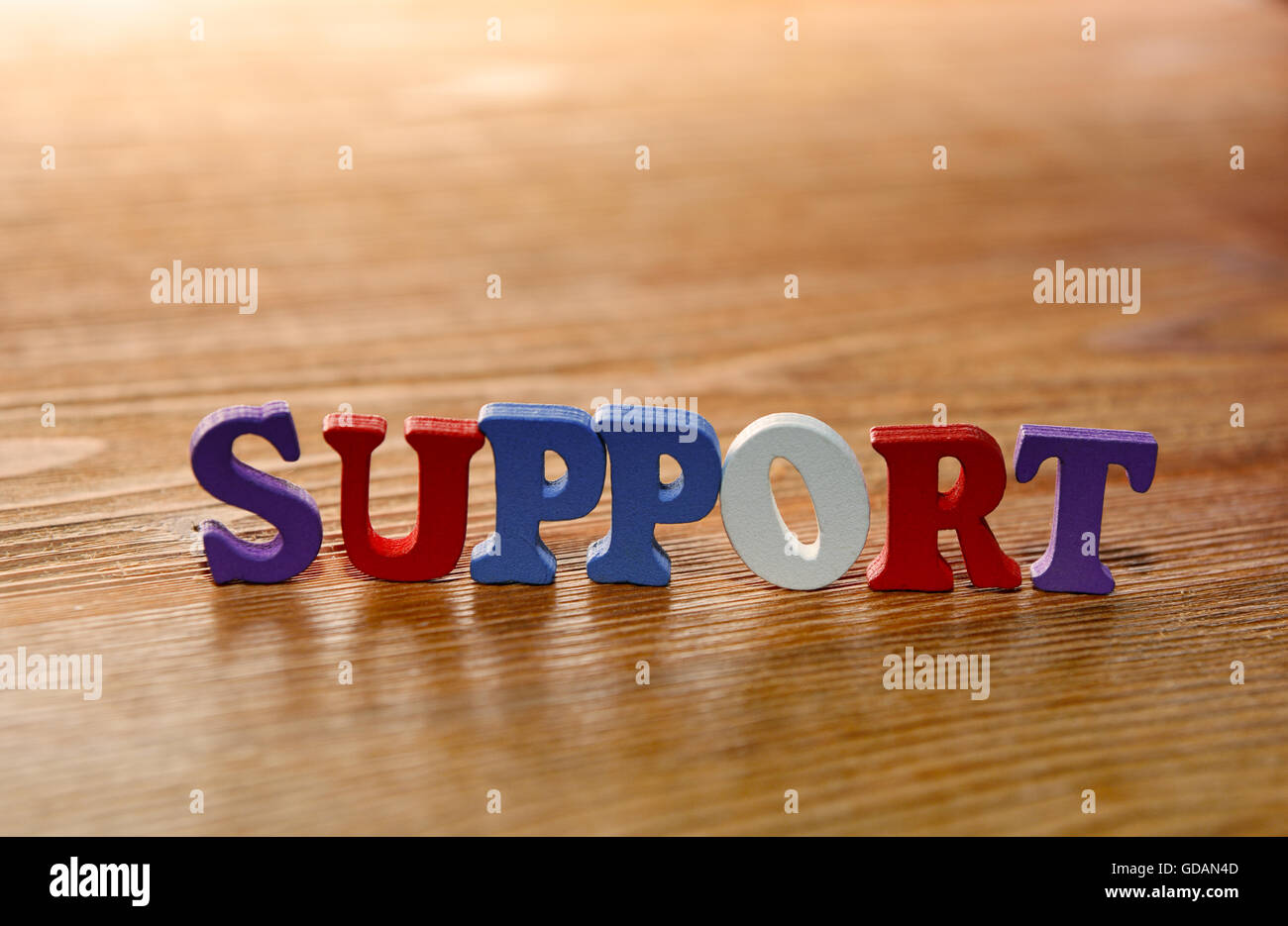 Supporto - parola fatta dal variopinto lettere sullo sfondo di legno di colore caldo Foto Stock