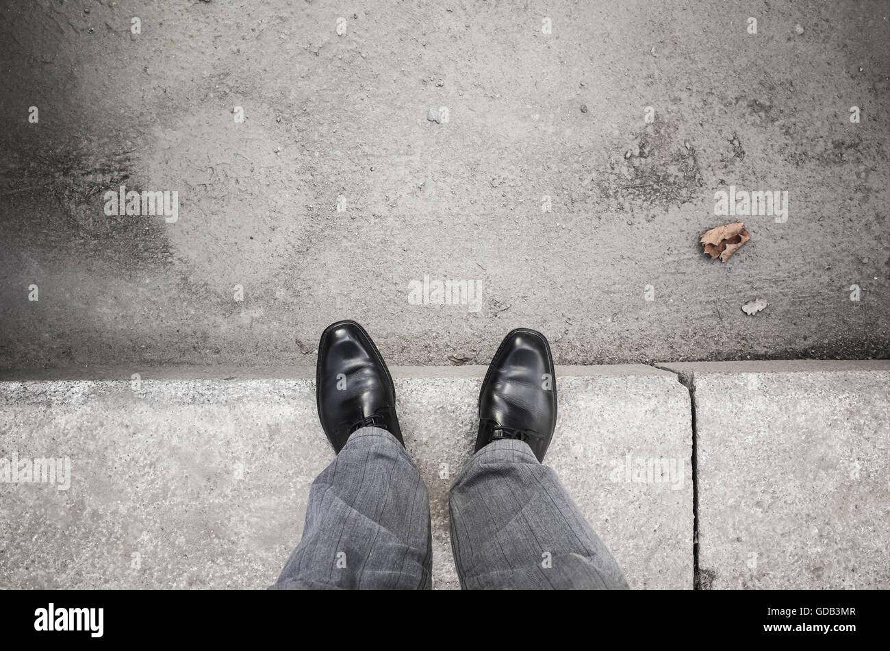 I piedi di un urbanite man in black nuovi fulgidi scarpe in piedi sul marciapiede grigio Foto Stock