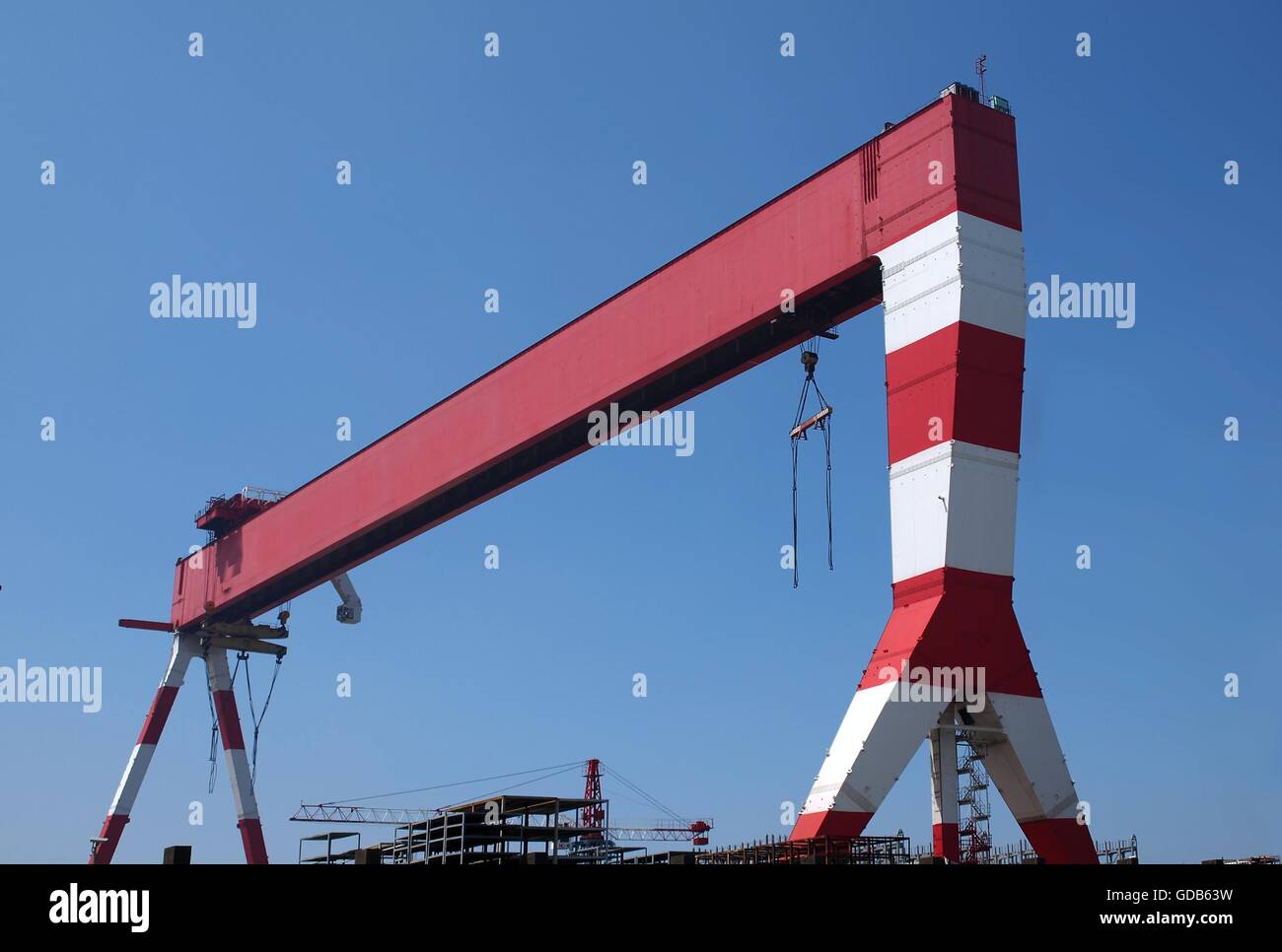 Un grande rosso e bianco gantry crane utilizzato per la costruzione navale Foto Stock