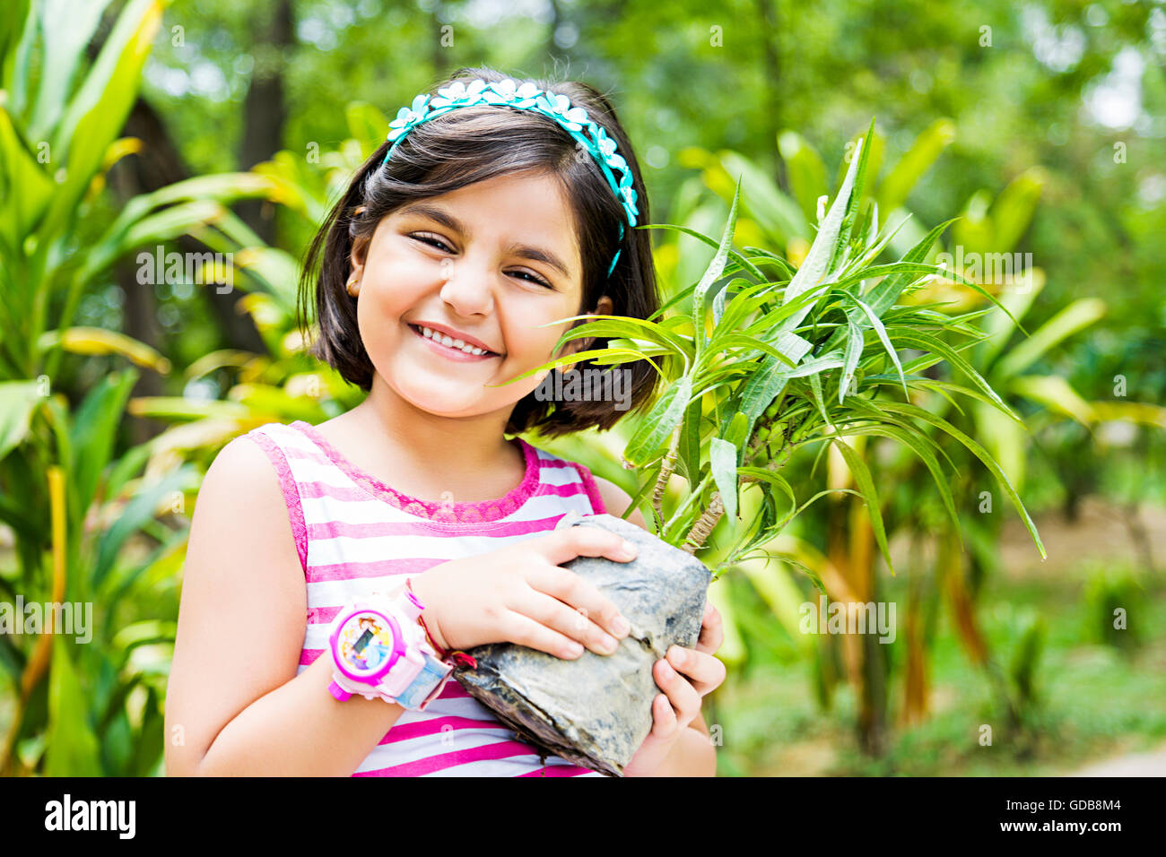 1 indian Kid ragazza azienda parco pianta in vaso Foto Stock