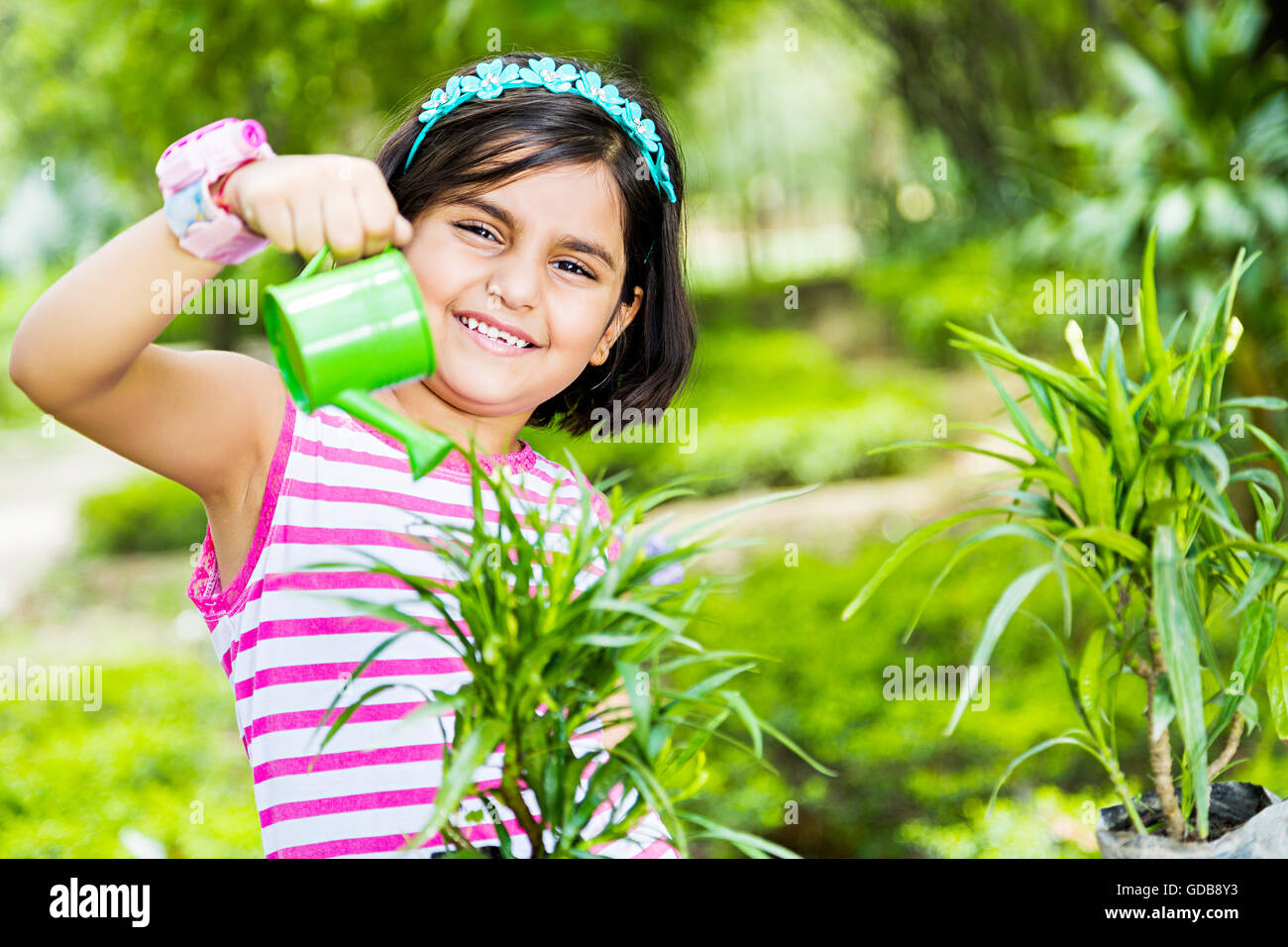 1 indian Kid girl park l'innaffiamento può versare acqua Foto Stock