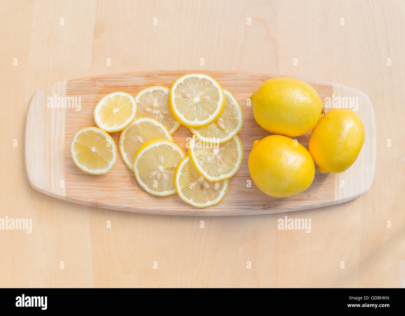 Un alto rotondo in vetro di succo di lime con lime tagliato a fette su un tagliere di legno. Foto Stock