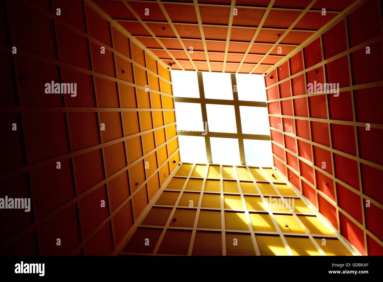 Vista prospettica della luce solare attraverso un lucernario che illumina il colorato soffitto geometrica del moderno atrium come sfondo astratto con spazio per la copia Foto Stock