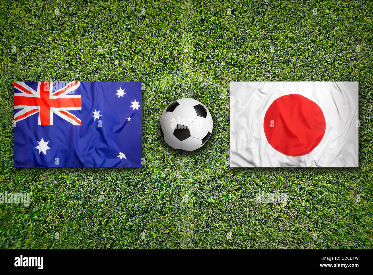 Australia vs. Giappone bandiere sul verde del campo di calcio Foto Stock