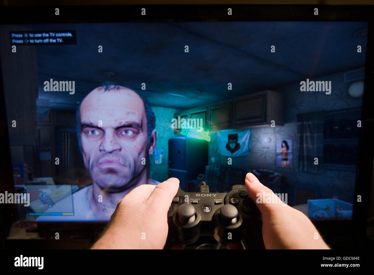 Due mani tenendo una Sony Playstation Controller davanti a uno schermo TV con Trevor dal Grand Theft Auto V video gioco Foto Stock