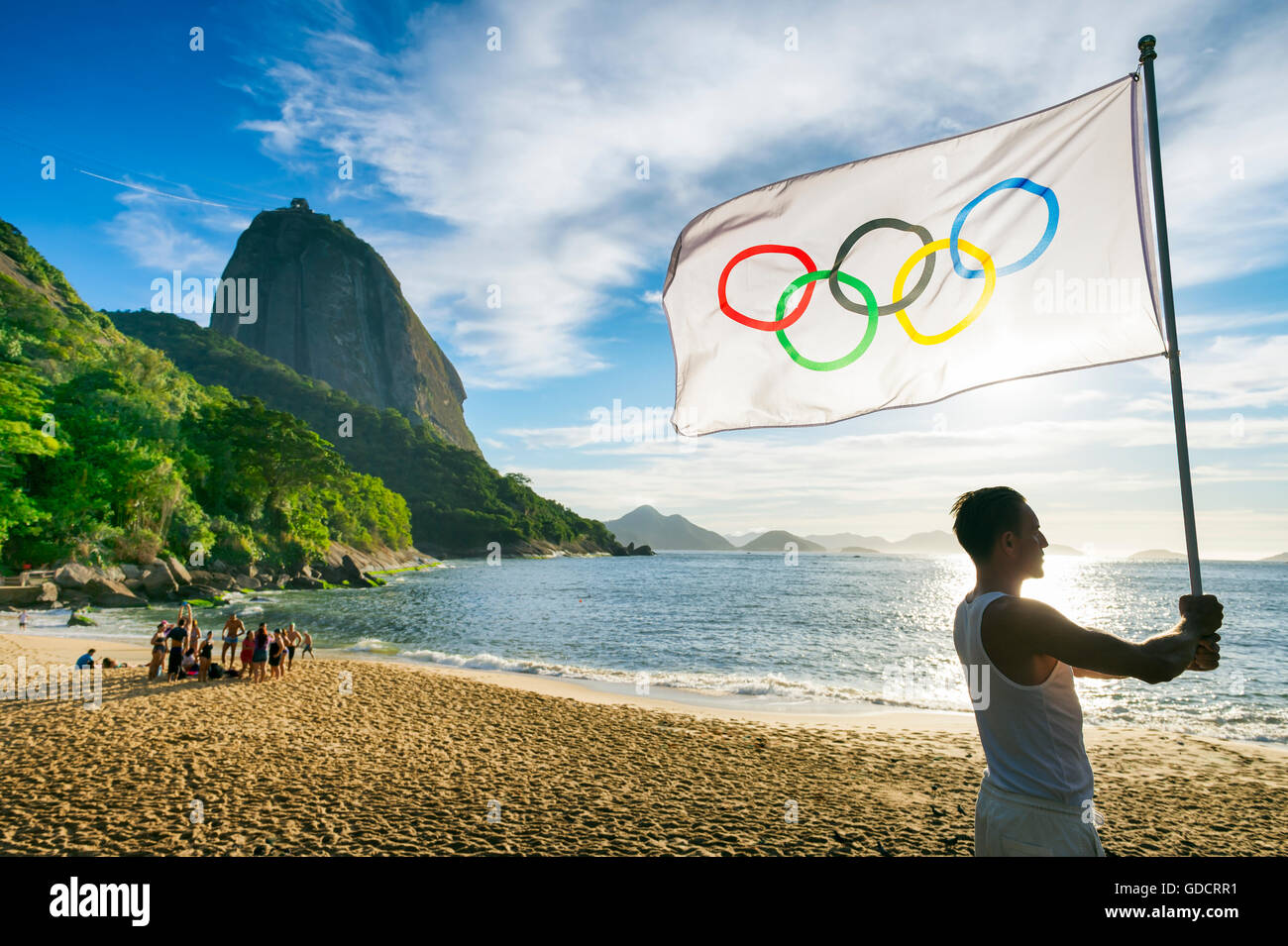 RIO DE JANEIRO - MARZO 24, 2015: atleta sorge in un profilo di sunrise silhouette a Red Beach tenendo una bandiera olimpica. Foto Stock
