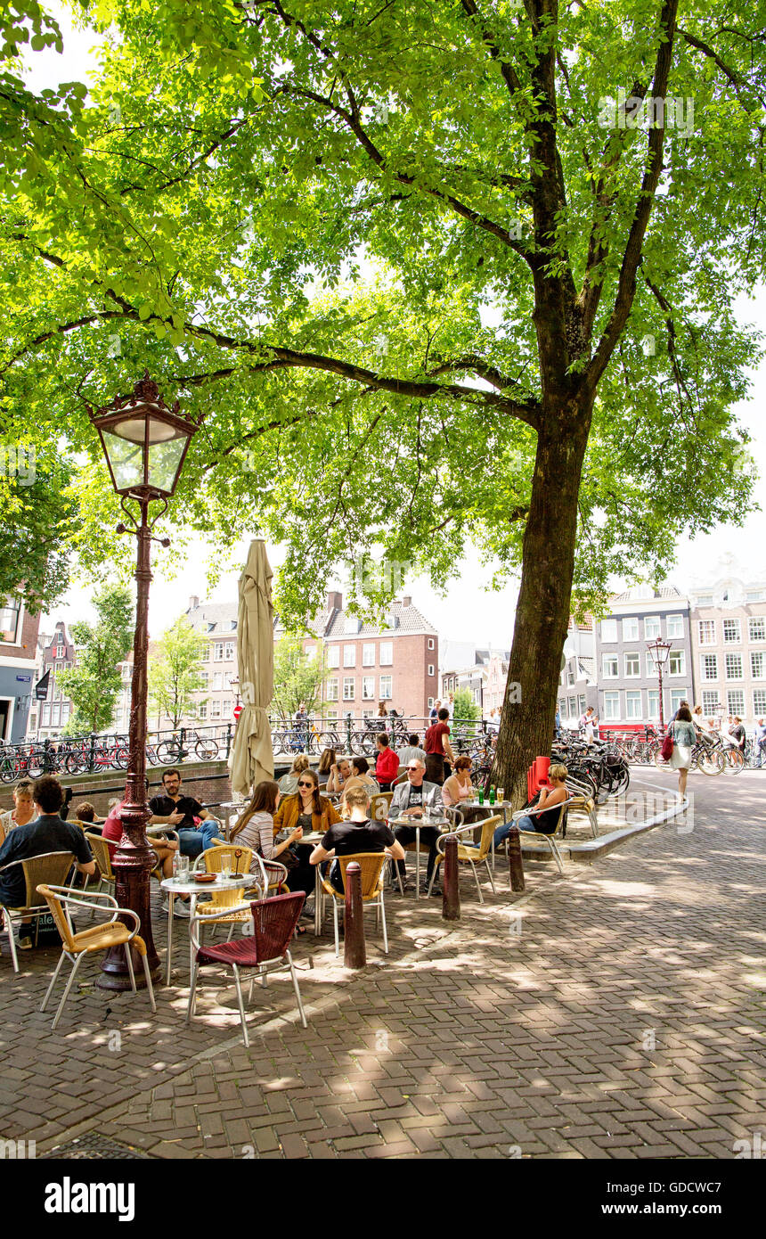 La gente seduta in una caffetteria dai canali Amsterdam Olanda Foto Stock