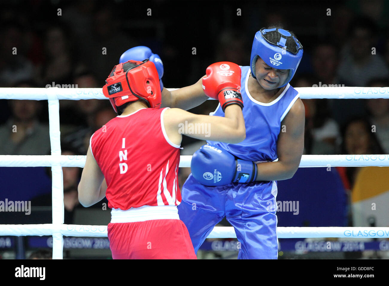 Devi Laishram dell India (rosso) compete contro Maria Machongua del Mozambico (blu) in campo femminile semifinale di peso leggero boxing (57-60kg) Concorrenza al 2014 giochi del Commonwealth a Glasgow. Devi Laishram dell India è andato sul vincere lo scontro. Foto Stock