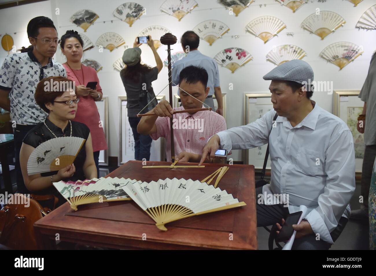 Pechino, Cina. Il 15 luglio 2016. Presidente di Pechino Fan Art Association Zheng Gao (C) anteriore dimostra le tecniche di fabbricazione di una ventola durante un festival culturale di ventole di piegatura a Pechino Capitale della Cina, 15 luglio, 2016. © Li Wen/Xinhua/Alamy Live News Foto Stock