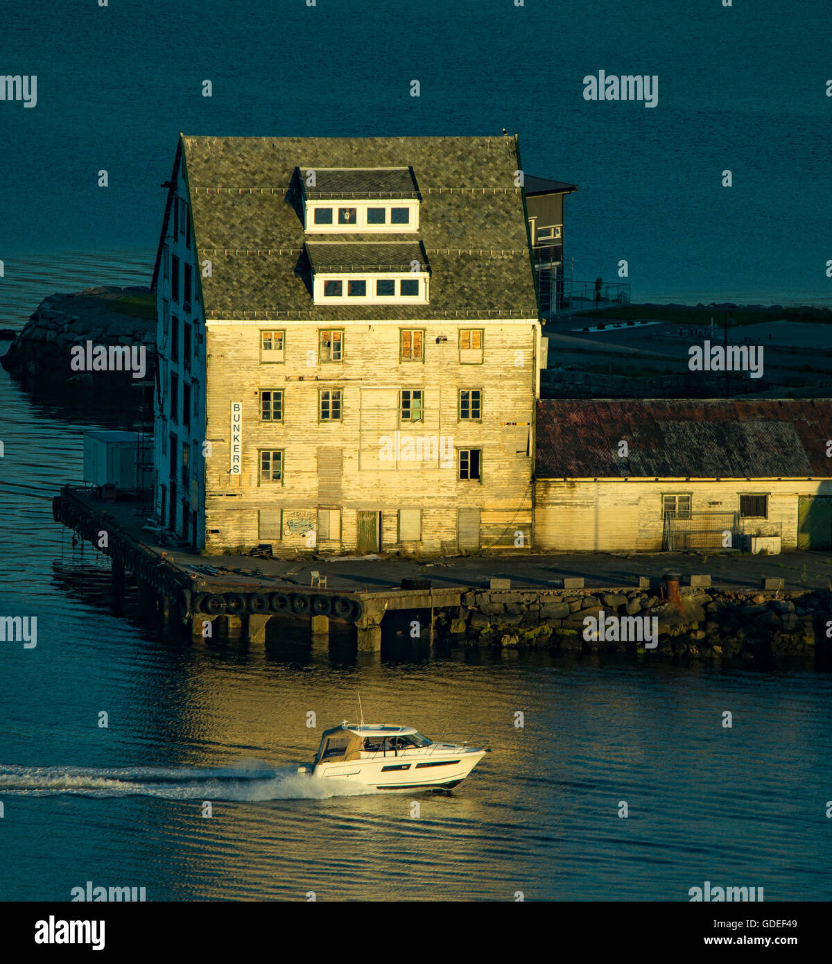 Vista nella luce della sera da Mt. Aksla di imbarcazione a motore accelerando dal vecchio magazzino in legno Alesund, Norvegia, più org Romsdal, Norvegia Foto Stock